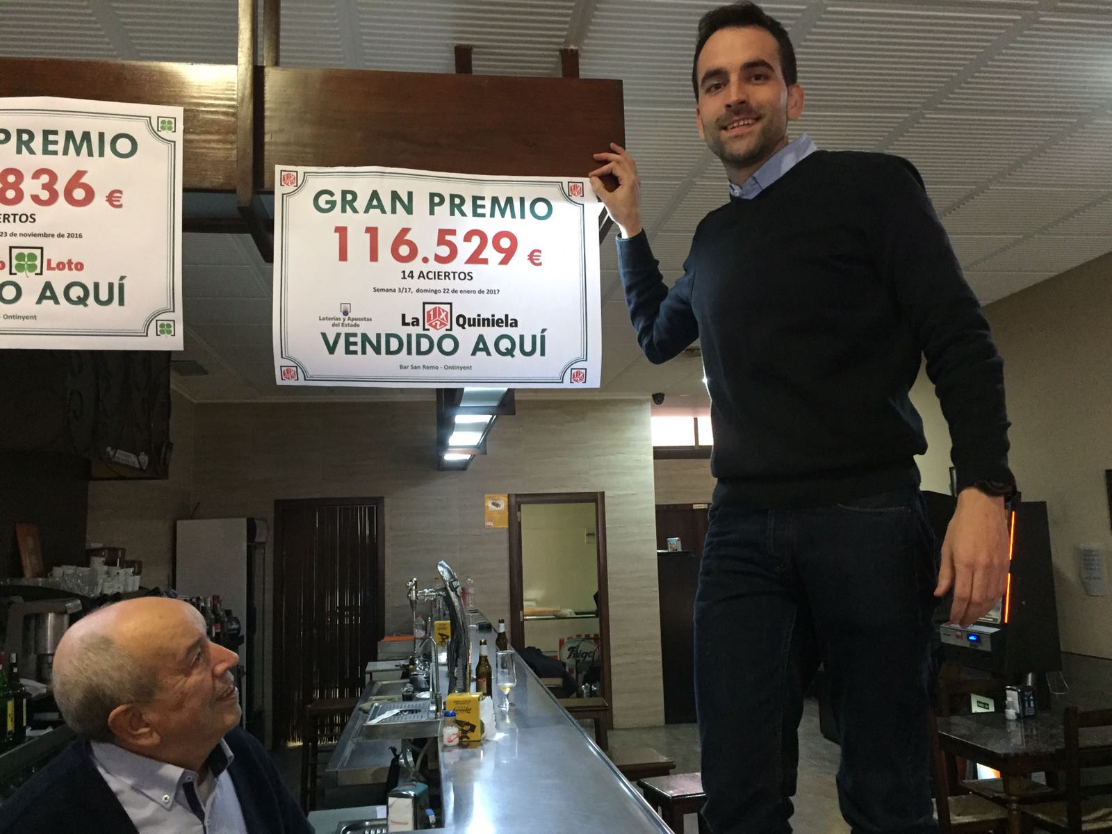 Propietarios del Bar San Remo de Ontinyent muestran el cartel con el premio de la Quiniela